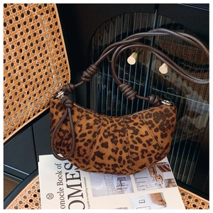 Detail of leopard print hobo bag with unique leather knotted strap on a rattan chair