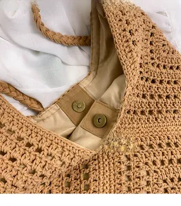 Detailed close-up of vintage metal magnetic buckles on a hand-woven straw tote bag