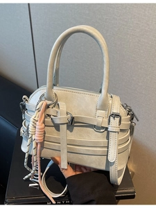 Minimalist light grey shell-shaped handbag with decorative straps and braided rope charm