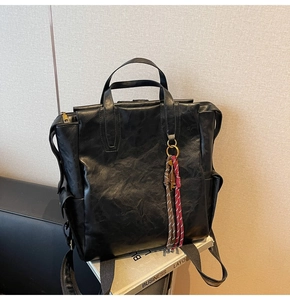Close-up of vintage black faux leather backpack with woven charm and gold hardware