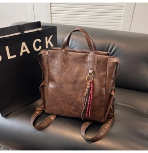 Detail of a dark brown vintage PU leather backpack with gloss texture and key pendant