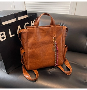Detail view of large vintage brown leather backpack with tennis racket charm and sturdy handle