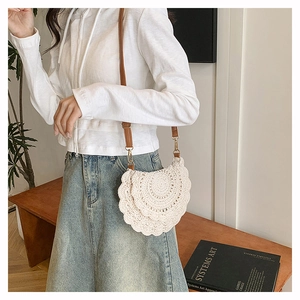Detail of bohemian cream crochet crossbody bag with layered lace pattern and leather strap