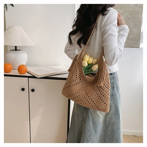 Close-up of brown straw woven tote bag with side tassels and hollowing craft textures