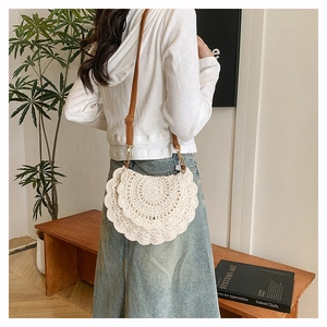 Detail showing the woven cotton crochet texture and ivory half-moon crossbody bag design