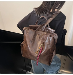 Detail of vintage brown leather backpack showing textured PU material and key pendant