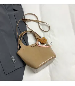 Detalle de bolso tote marrón claro con colgante de oso y nudo tejido decorativo