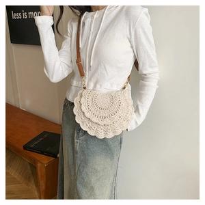 Detail of bohemian ivory crochet crossbody bag with layered lace and brown leather strap