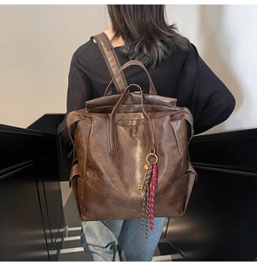 Detailed back view of a large vintage brown leather backpack with key and braided charms