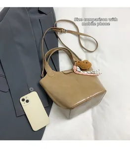 Detalle de bolso cubo de cuero marrón con colgante de oso y móvil para comparar talla