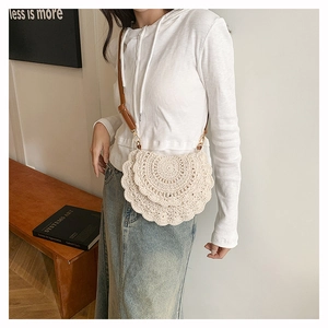 Close-up of bohemian semi-circle woven crochet bag with brown leather strap detail