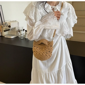 Detail der handgewebten khakifarbenen Beuteltasche mit Flechtriemen auf weißem Kleid