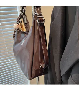 Deep brown glossy leather tote bag featuring a baseball glove and bat charm detail