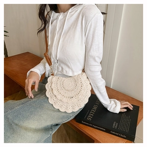 Close-up of bohemian beige crochet shoulder bag with layered lace texture and leather strap