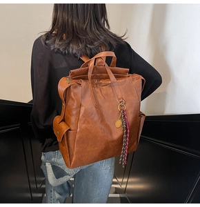 Detail of vintage brown PU leather backpack with gold tennis racket charm and tassel