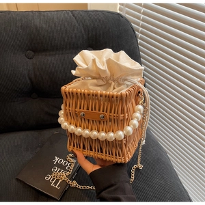 Detail of hand-woven rattan bucket bag with elegant pearl handle and gold chain strap