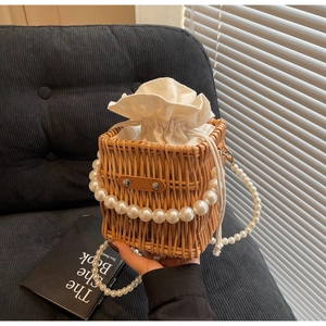 Detail of straw woven bag featuring white drawstring liner and elegant pearl handle