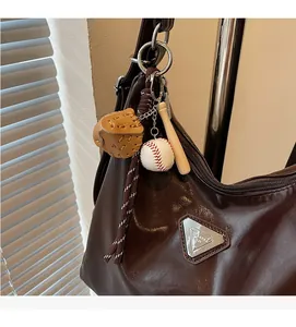 Detail of baseball charm with bat and glove hanging on an oil wax leather tote bag