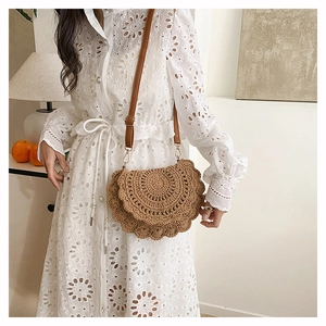 Detail of bohemian woven crossbody bag with wavy lace edges on a white eyelet dress