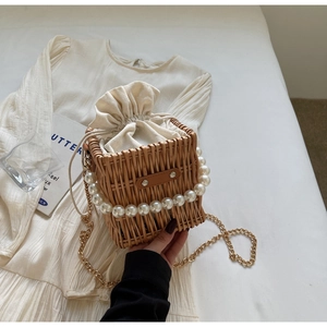 Close-up of woven straw bag with pearl handle and canvas drawstring lining detail