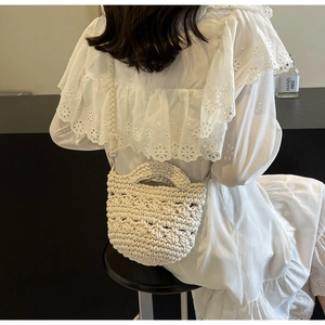 Detail der handgewebten cremeweißen Umhängetasche mit grober Strickstruktur und Trageriemen