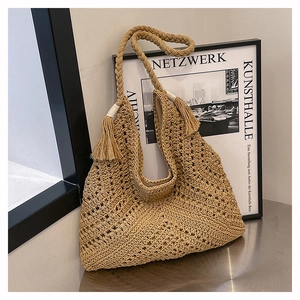 Detailed close-up of hollow crochet texture and fringe tassels on a straw tote bag