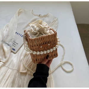 Detail of woven straw bag featuring pearl handle and drawstring canvas lining