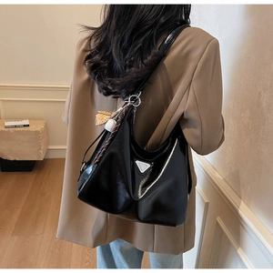 Detail of black glossy hobo bag with silver triangle plaque and star bag charm