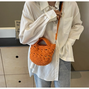 Detail der orangefarbenen handgestrickten Eimertasche mit Webstruktur und Gurt