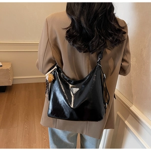 Glossy black leather hobo tote bag featuring a silver triangle logo and orange charm