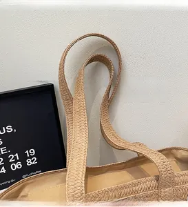 Close-up of dual straw woven shoulder straps and smooth fabric lining on tote bag
