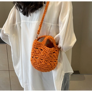 Detail der orangefarbenen handgestrickten Häkeltasche mit Webstruktur und Gurt