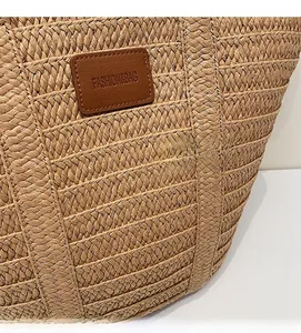 Macro detail of hand-woven straw shoulder bag with a brown leather logo patch
