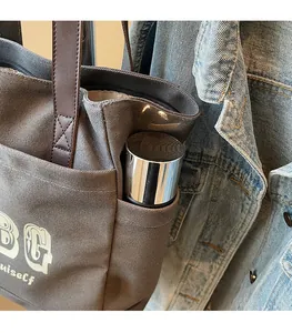 Dettaglio della tasca laterale della borsa in tela con borraccia e manici in pelle