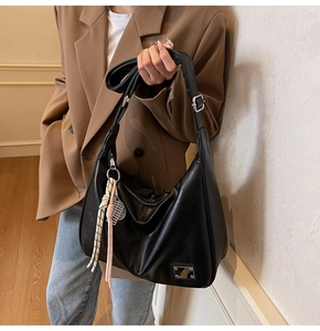 Detail of black leather Hobo bag featuring silver hardware and woven tassel accessory