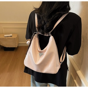 Detail view of pink patent leather tote being worn as a backpack with a metal plaque