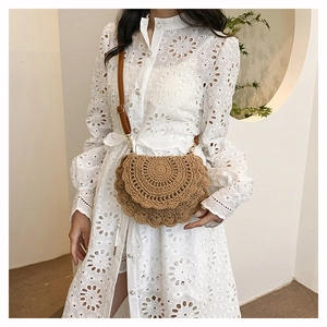 Detail of bohemian hand-woven straw crossbody bag with brown leather shoulder strap