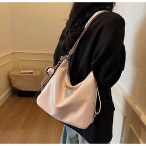 Close-up of pink patent leather hobo bag with metal logo and baseball pendant charm