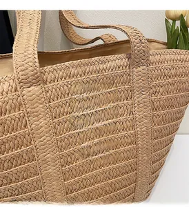 Close-up of a woven straw tote bag featuring a brown leather fashion patch and natural texture