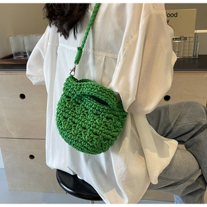 Detailstruktur der leuchtend grünen handgewebten Beuteltasche mit Metallhaken und Gurt