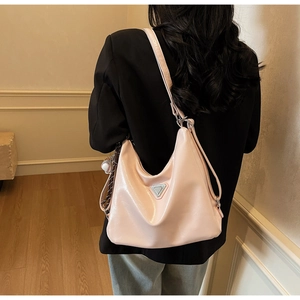 Detail of pink hobo shoulder bag with silver triangle logo and baseball charm