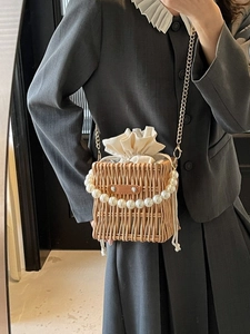 Chic straw bucket bag with elegant pearl handle and gold chain strap for women
