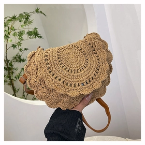 Detail of bohemian hand-woven straw bag with petal-shaped flap and adjustable strap