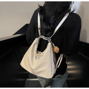 Detail of cream white leather backpack with silver triangle logo and cute charm