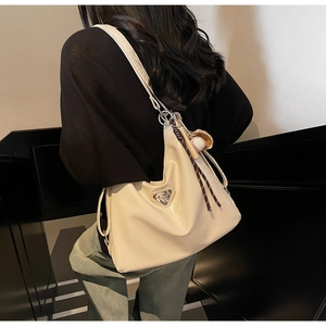 Close-up of cream minimalist tote bag with leather texture and baseball pendant detail