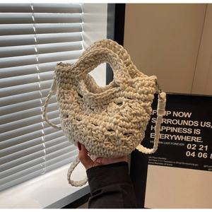 Detail der handgewebten cremefarbenen Beuteltasche mit Strickstruktur und Schultergurt