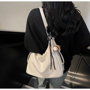 Macro shot of cream large hobo bag with sporty baseball charms and triangle metal tag