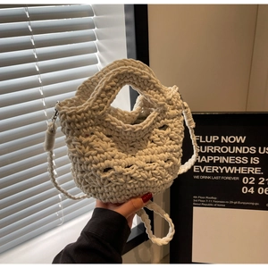 Nahaufnahme einer cremefarbenen gewebten Beuteltasche mit handgestrickter Textur und Riemen
