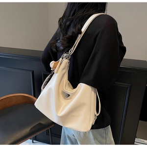 Macro shot showing the cream white tote bag with metal logo and baseball pendant detail