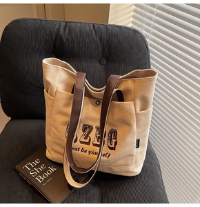 Dettaglio della borsa tote in tela beige con manici in pelle marrone e tasche laterali